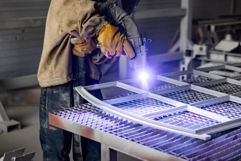 Medewerker schoopt een metalen hekwerk voor duurzame bescherming