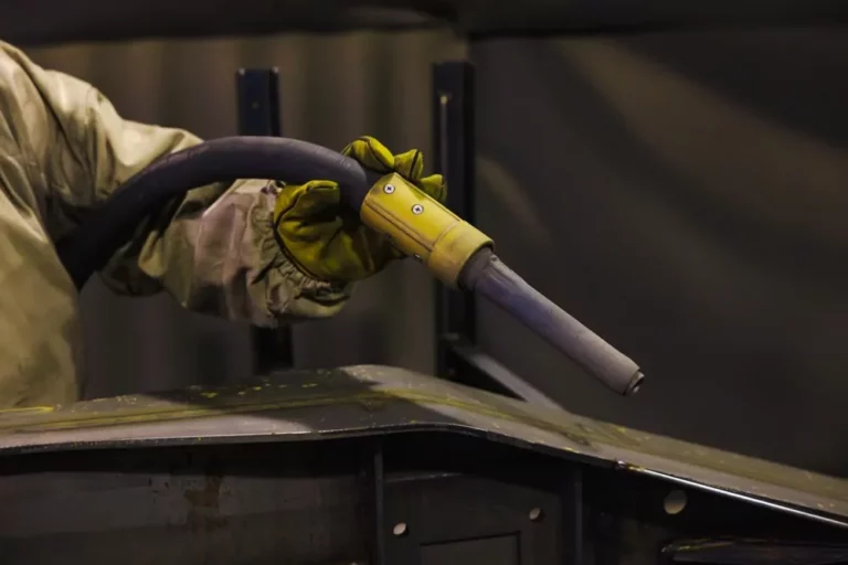 Medewerker voert straalwerk uit aan een metalen onderdeel