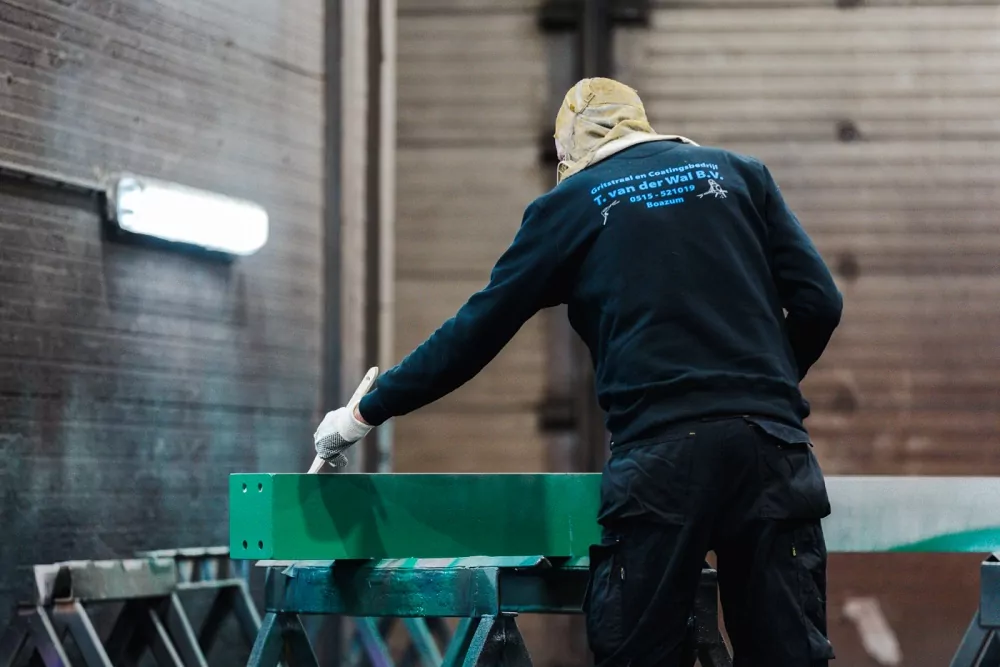 Medewerker van T. van der Wal B.V. aan het werk in de coatinghal